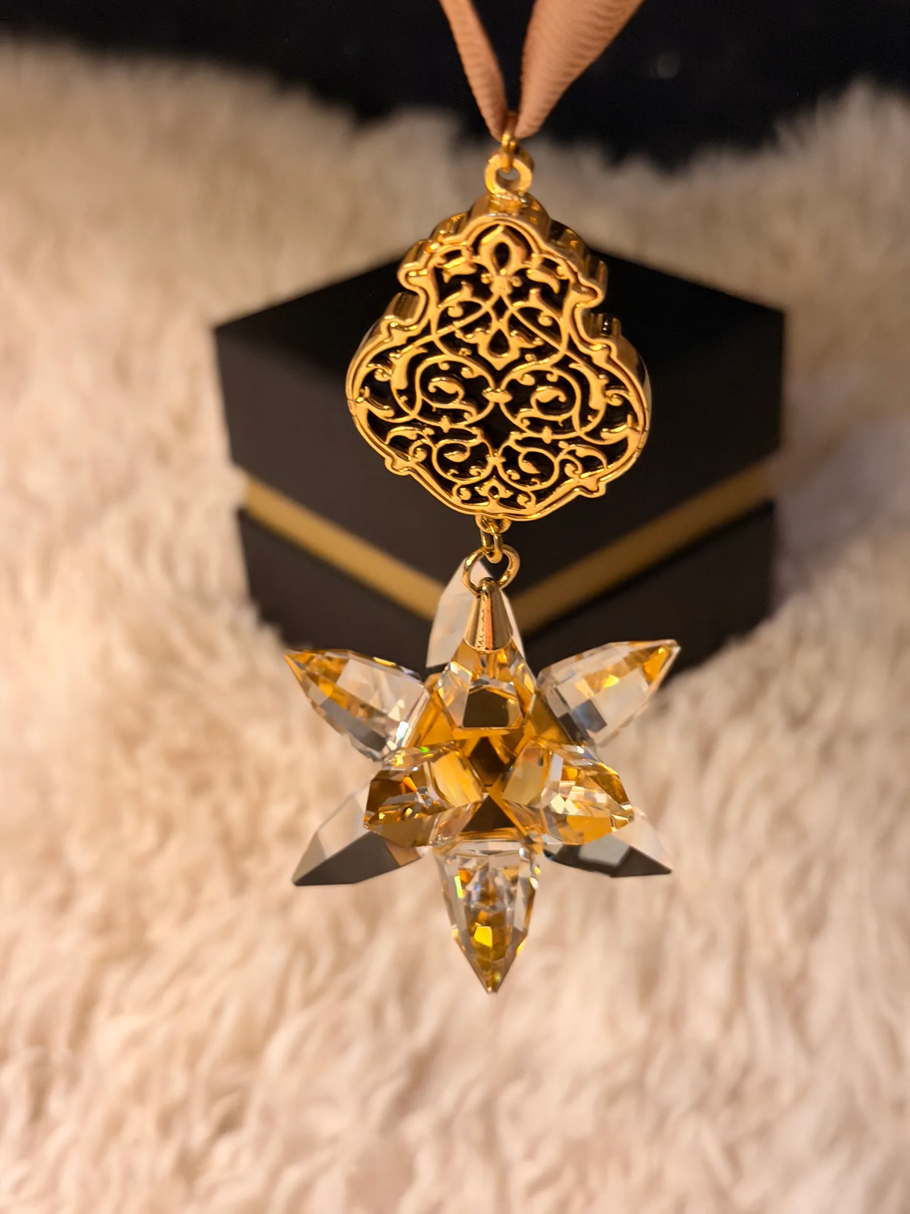 Hanging ornament: golden crystal star beneath a gold-tone filigree top piece on a ribbon