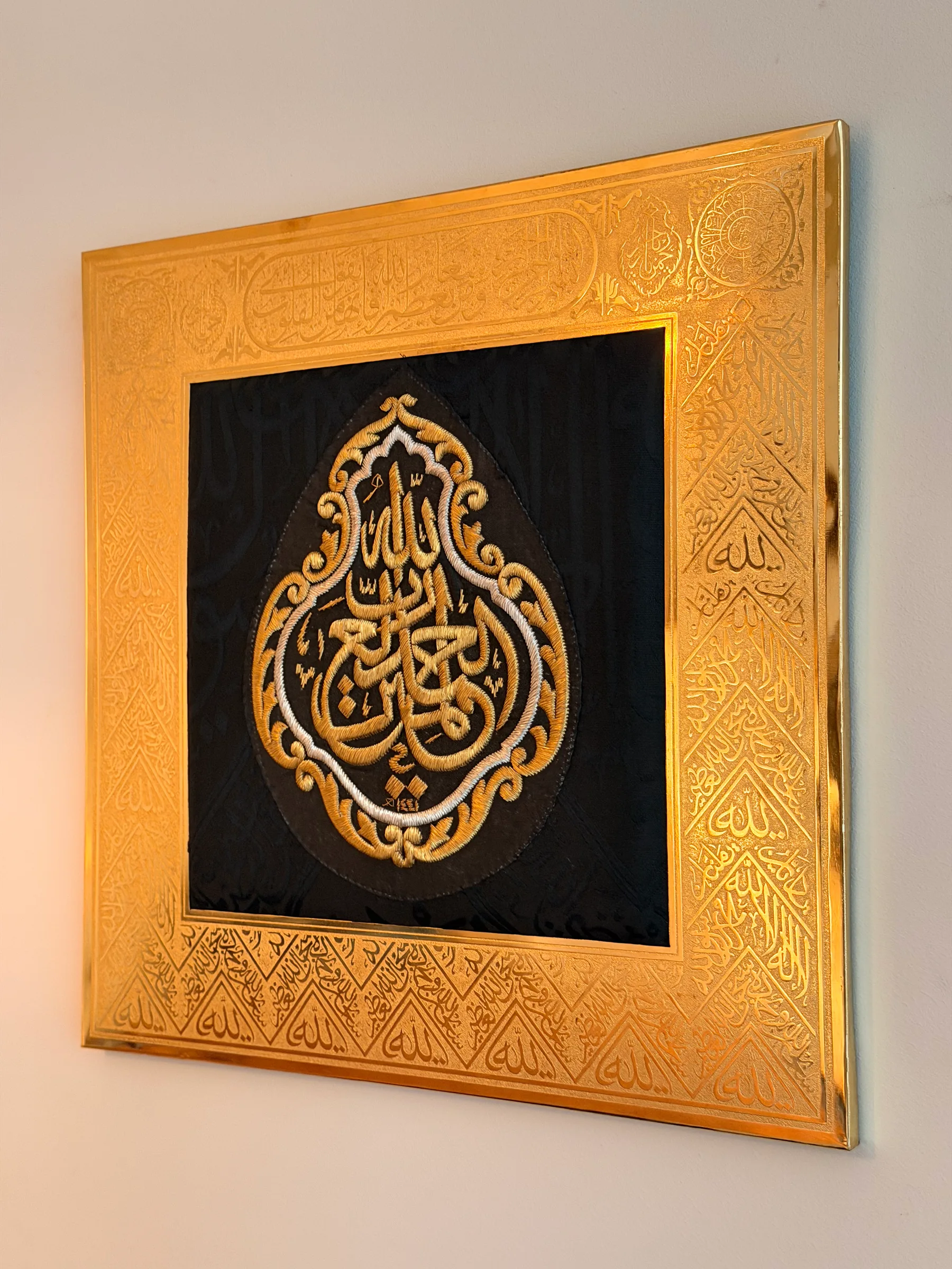 Large Kiswah frame at an angle with light reflecting off the gilded engraving